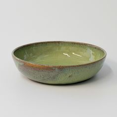 a green bowl sitting on top of a white table