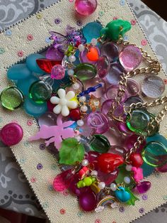 a bunch of different colored glass beads on a doily with flowers and butterfly charms