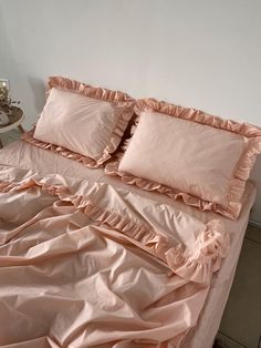 a bed with pink ruffled sheets and pillows