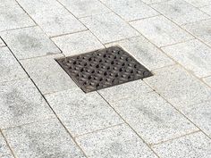 a manhole cover on the ground in front of a sidewalk with a drain grate