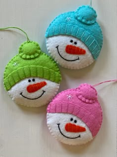 three snowman ornaments are hanging on a table