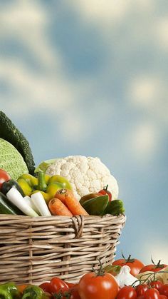 a basket filled with lots of different types of vegetables next to other fruits and vegetables