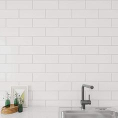 a kitchen with white subway tile on the wall and stainless steel faucet in the sink