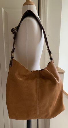 This bag is very soft, very slouchy unlined pebblegrain. Color Cognac, with brass hardware, Dark Brown harness-quality shoulder strap with Ivory topstitching. Shoulder strap is 2 1/2" wide at the shoulder tapering to 1 1/4" wide at the ends; attachments are the same leather as the strap. Bag has an open interior which closes with a single leather-mounted snap. Bag has attached unlined pebblegrain flat pouch with a single snap close for carrying smaller items. My apologies for the poor interior shot; because of the bag's slouchiness I was unable to adequately hold it open with one hand while photographing it.  Please Note: The bag's dimensions have been taken utilizing its side and bottom construction seams.  Dimensions: Length, measured across the top at maximum length 19" Width, measured Classic Hobo Bag With Double Handle And Adjustable Strap, Classic Hobo Bag With Adjustable Strap And Double Handle, Beige Leather Hobo Bag With Adjustable Strap, Fall Shoulder Bag With Detachable Strap In Pebbled Leather, Everyday Textured Leather Hobo Bag For Fall, Brown Pebbled Leather Shoulder Bag With Gold-tone Hardware, Beige Bags With Brass Hardware For Daily Use, Everyday Fall Textured Leather Hobo Bag, Daily Beige Bags With Brass Hardware