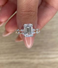 a woman's hand holding a ring with an emerald and diamond band on it