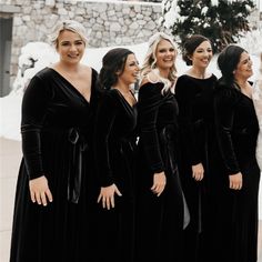 a group of women standing next to each other wearing black dresses and smiling at the camera