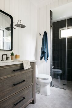 Hexagonal grey tile floors contrast well with the dark tiled shower space and white walls of this bathroom space.