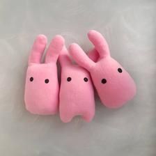 three pink stuffed animals sitting next to each other on top of a white surface with black dots