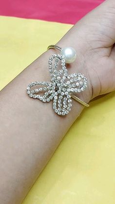 a woman's arm with a pearl and diamond cross bracelet on top of it