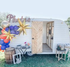 a party trailer with balloons and stars on the wall, next to a small table