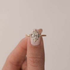 a woman's hand holding a ring with a diamond in the middle and a white background