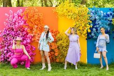 three women are standing in front of colorful flowers