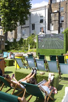 people are lounging in lawn chairs watching movies