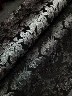 black and silver fabric with white flowers on the bottom, along with dark grey background