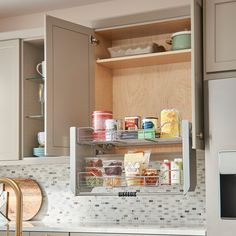 an open cabinet in a kitchen with food items on the shelves and dishes below it