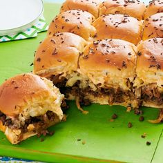 several sliders cut in half on a green cutting board