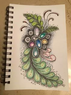 a spiral notebook with an image of a peacock's feathers and eggs on it