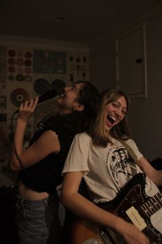 two young women singing and playing guitar together