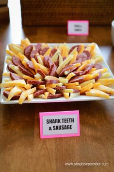 a plate full of french fries on a table with a sign that says shark teeth and sausage