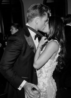 a man in a tuxedo kisses a woman's face as they stand next to each other