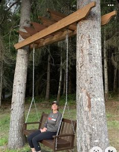 a woman is sitting on a swing in the woods