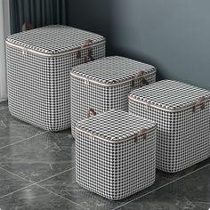 three black and white baskets sitting next to each other on the floor in front of a window