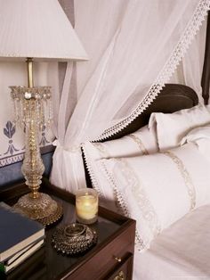 a bed with white sheets and pillows next to a night stand