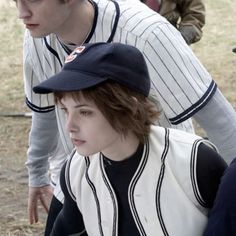 two young men in baseball uniforms standing next to each other, one wearing a hat