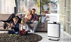 a family sitting on a couch in front of an air purificater