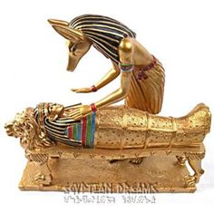 an egyptian figurine laying on top of a golden bench