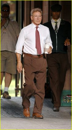 an older man walking down the street with a cup of coffee in his hand and two other men behind him