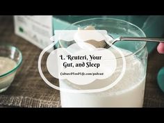 a person holding a spoon over a glass filled with milk