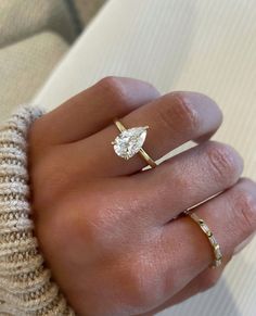 a woman's hand with two gold rings and a diamond ring on her finger