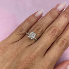 a woman's hand with a diamond ring on top of her finger and the other hand holding an engagement ring