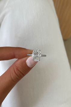 a woman's hand holding an engagement ring with a diamond in the center on top of her finger