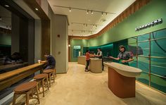 two people are standing at the counter in a restaurant with green walls and wooden stools