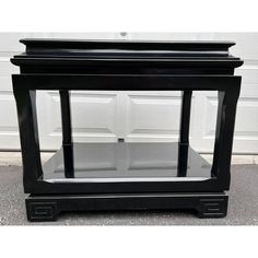 a black end table with two shelves on each side and an open door behind it