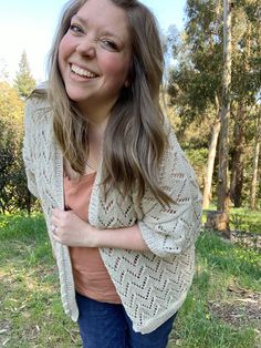 a woman standing in the grass with her hands on her hips and smiling at the camera