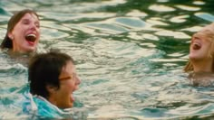 two people are in the water and one is laughing with his mouth open while another man looks on