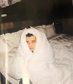 a man wrapped in a blanket on top of a bed