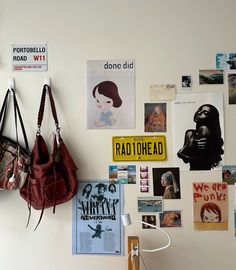 there are many posters on the wall with purses hanging from it's hooks