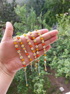 a hand holding some beads in it's left hand and trees in the background