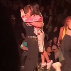 two people hugging each other in front of an audience at a dance event, with one person standing up and the other sitting down