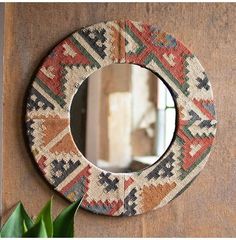 a round mirror hanging on the side of a wall next to a potted plant