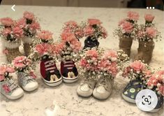 several pairs of baby's shoes with flowers in them sitting on a counter top