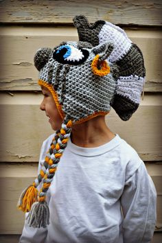 a young boy wearing a knitted hat with an animal on it's side