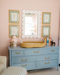 a baby's room with a dresser, mirror and toy crib in it