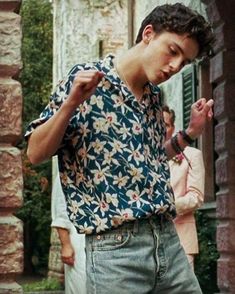 a young man standing in front of a building with his hand on his hip and looking down