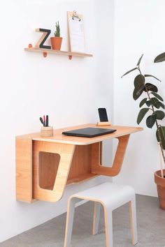 a wooden desk with a laptop on top of it next to a potted plant