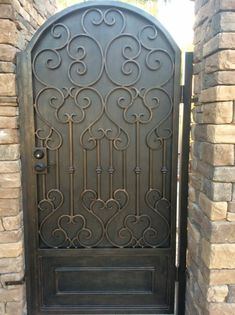 an iron gate is shown in front of a brick wall and stone pillars with decorative designs